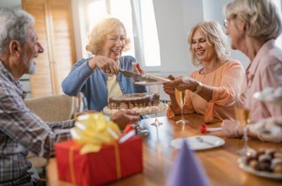 Des personnes âgées rient et mangent un gâteau autour d'une table